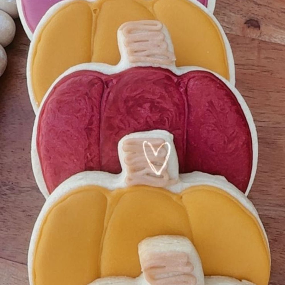 Galletas de calabaza en fila, glaseadas en vino y mostaza, con el rabito en relieve